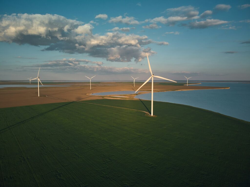 Aerial view of wind turbines and agriculture field near the sea at sunset